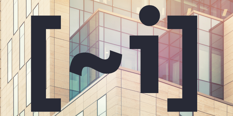 The text “~i” inside a pair of square brackets in front of a highly geometrical building.