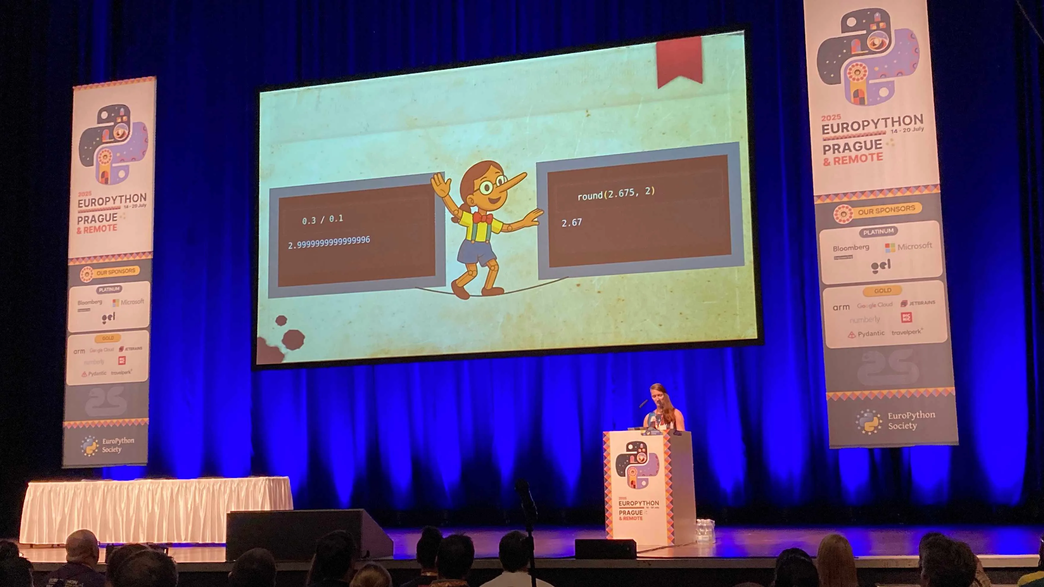 A picture from the EuroPython main stage with a single speaker behind the podium. The slide shows a joyful Pynocchia wooden girl between two snippets of Python code showing two instances of odd behaviour of Python floats.