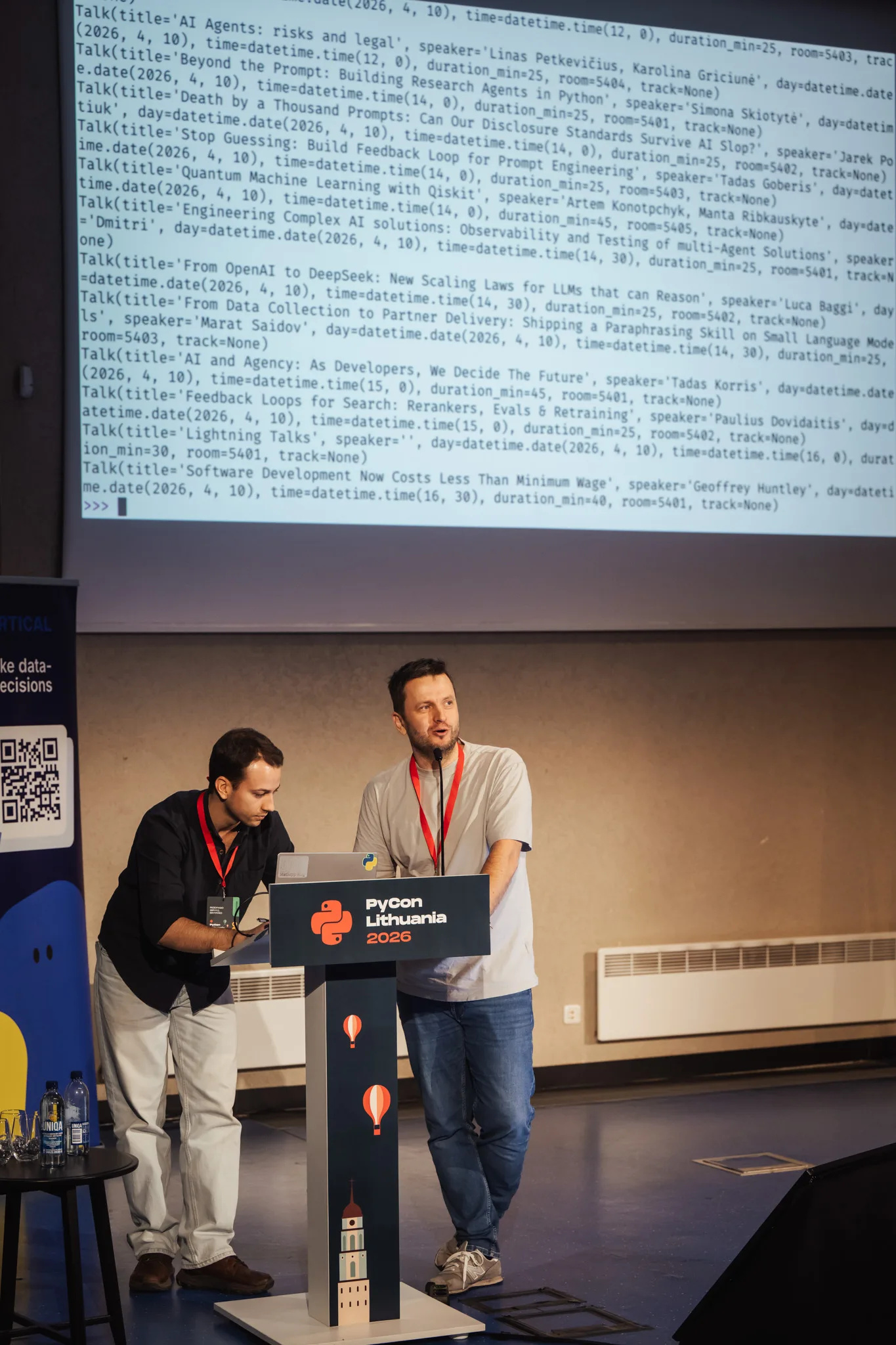 Rodrigo typing while Aidis presents. Aidis Stukas and Rodrigo Girão Serrão at PyCon Lithuania presenting the package pycon-lithuania.