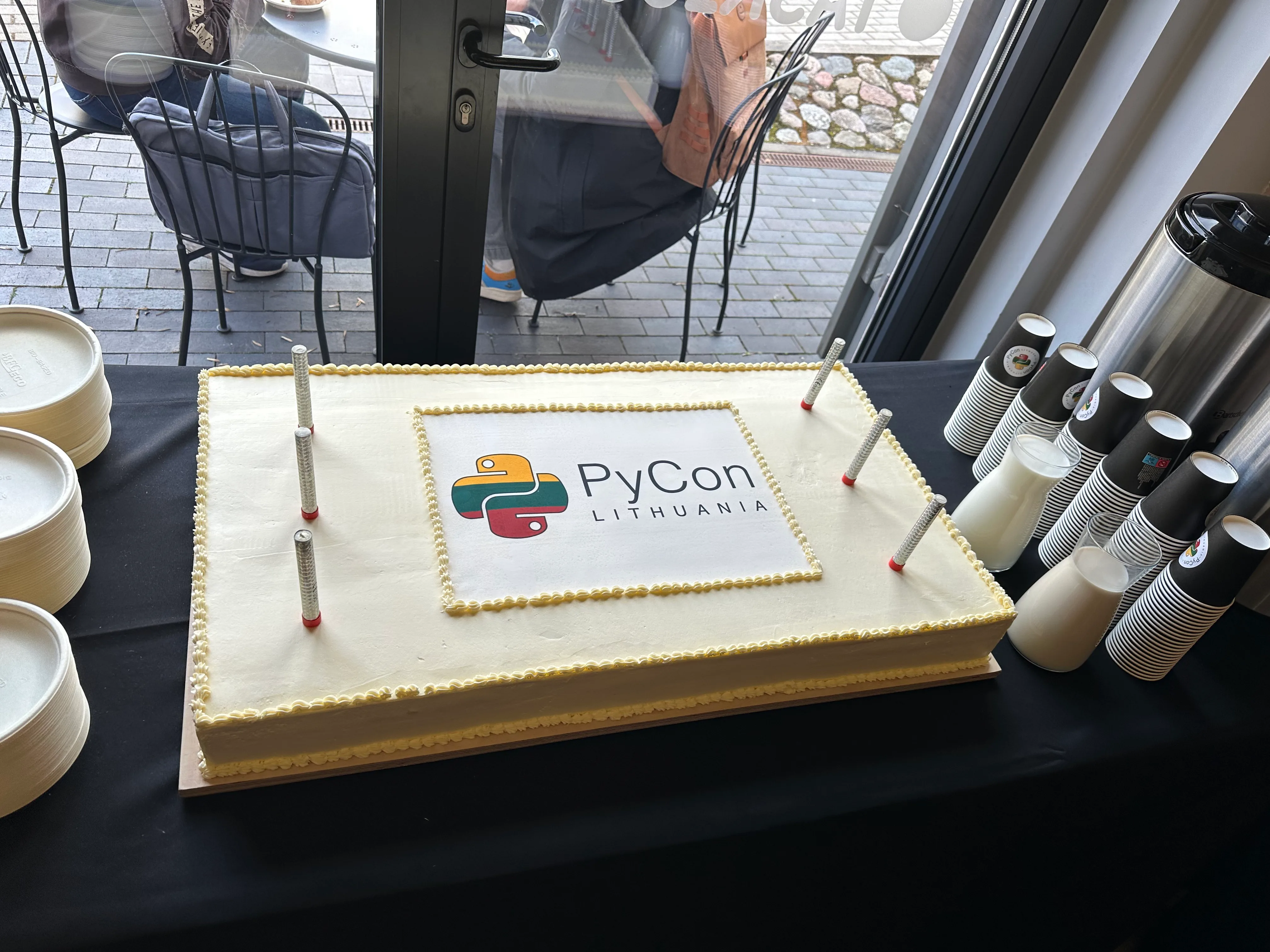 A picture of a large rectangular cake with the PyCon Lithuania logo in the middle.